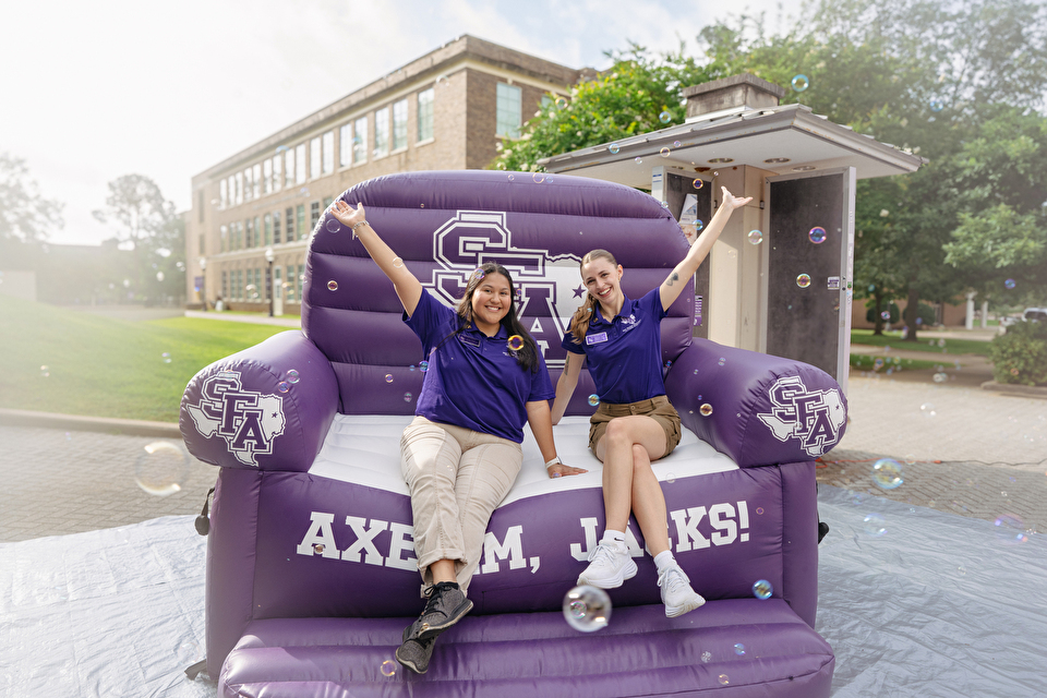 Two students pose in a giant inflatable SFA chair