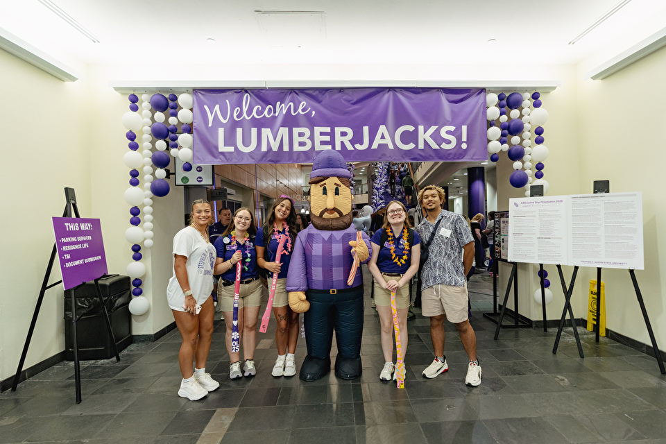 Students stand with Lenny the Lumberjack in front of a banner that reads "Welcome Lumberjacks!"