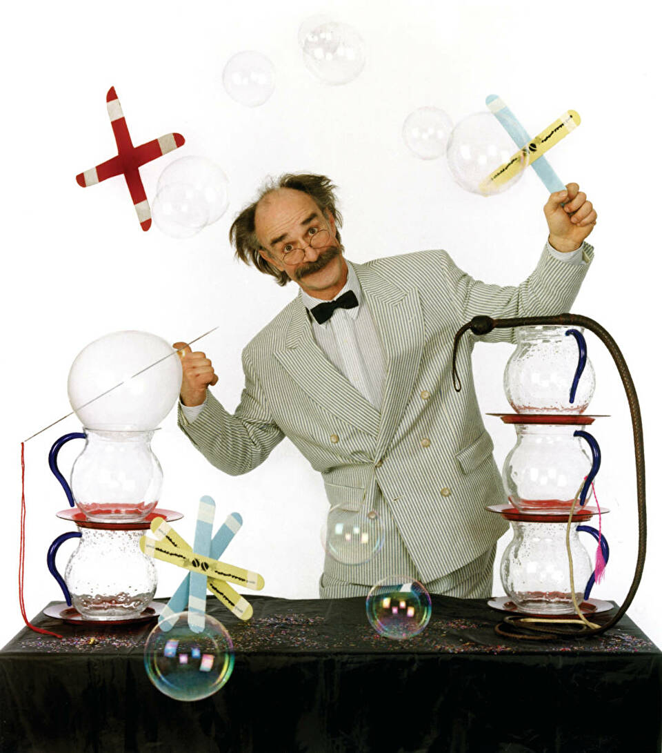 Mr. Fish juggles an assortment of experiments with boomerangs, test tubes, and bubbles.